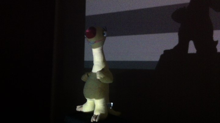 Footage of the scanner running: Gray-coded stripe patterns projected onto the object on the turntable in a darkened room, stepping from coarse bands to fine lines.